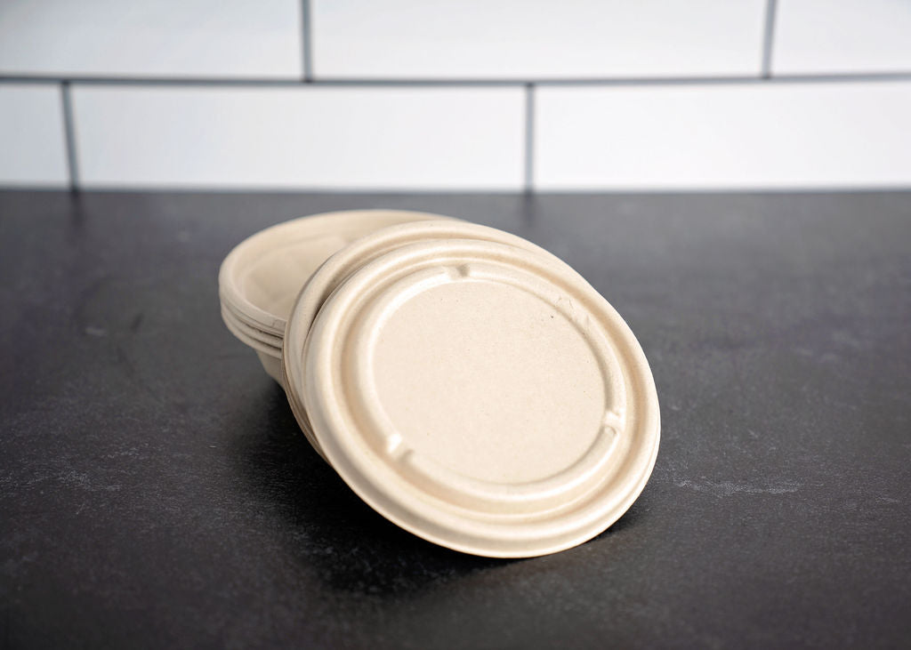 A stack of round beige biodegradable paper cup lids